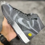 نمای نزدیک کتونی جردن فامیلیا ذغالی در دست، طرح گل‌دار کنار swoosh و جزئیات زرد